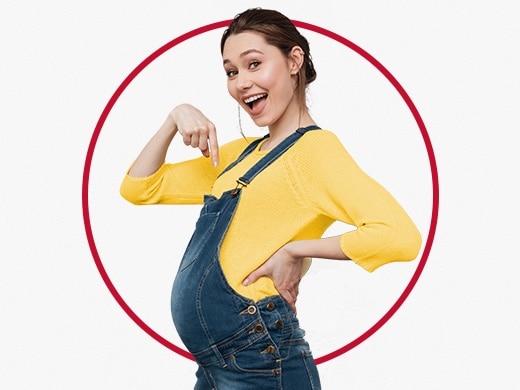 Happy young pregnant woman wearing yellow jumper and pointing to her tummy